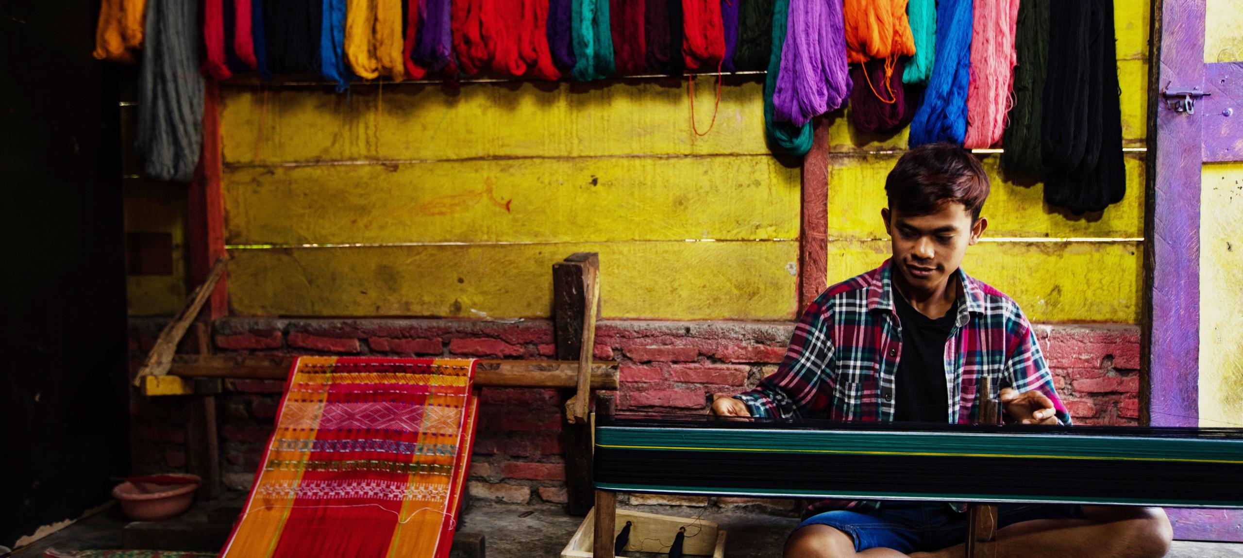 Candro Sitorus, a Ulos weaver from North Tapanuli in North Sumatra province, is performing mangani, a crucial stage in the Ulos-making process. Photo by Simon Siregar. Courtesy of UNESCO.
