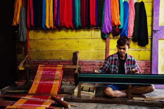 Candro Sitorus, a Ulos weaver from North Tapanuli in North Sumatra province, is performing mangani, a crucial stage in the Ulos-making process. Photo by Simon Siregar. Courtesy of UNESCO.